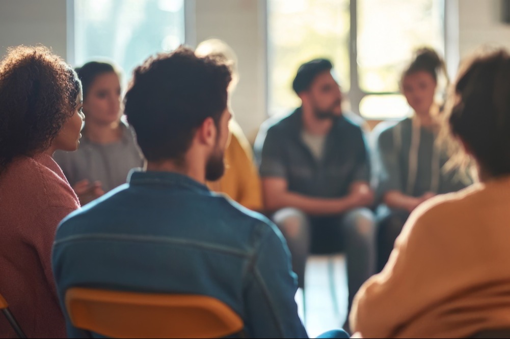 Group of diverse people sitting in a circle, listening and talking with each other